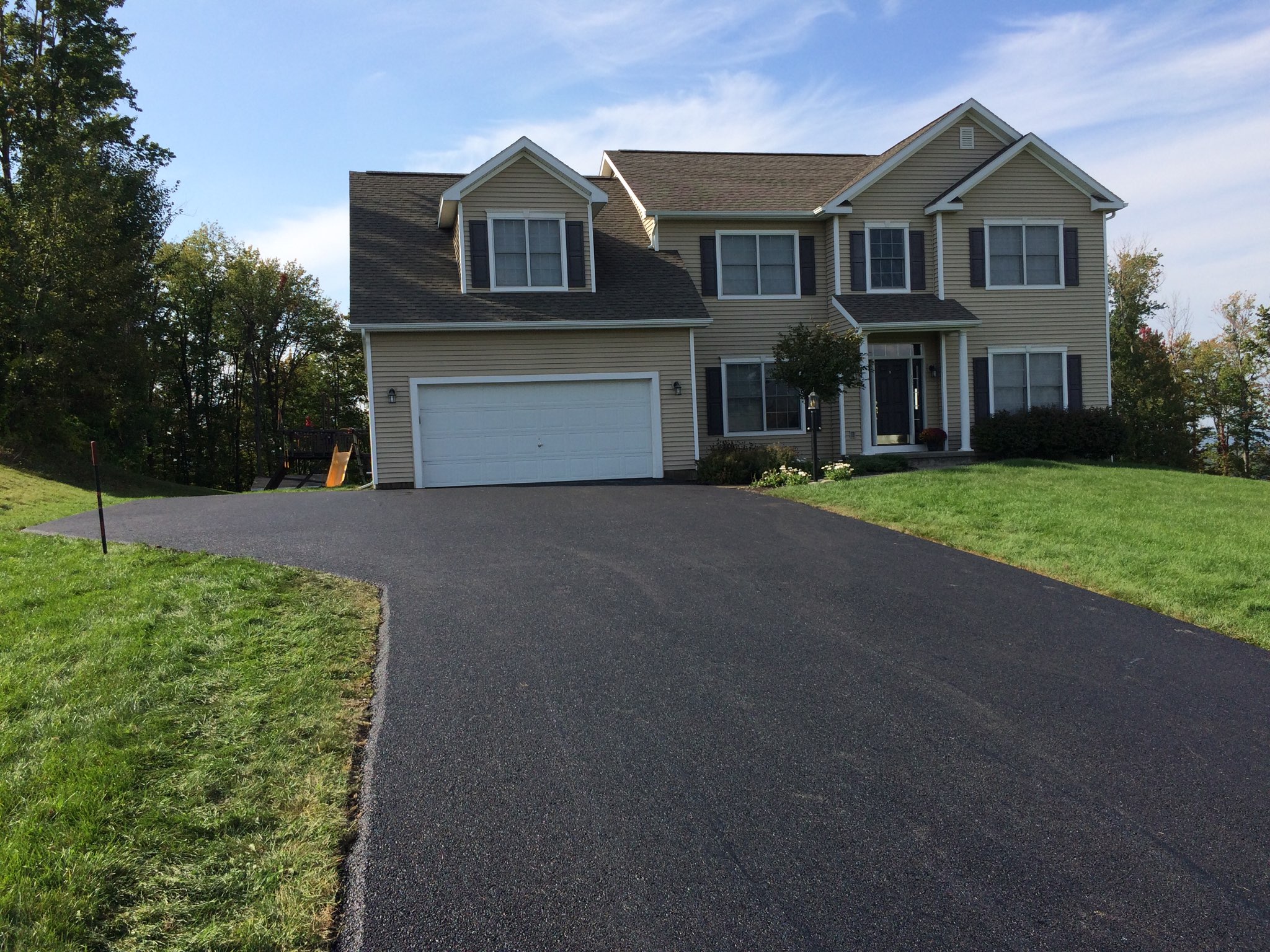 A tan house with a new asphalt driveway