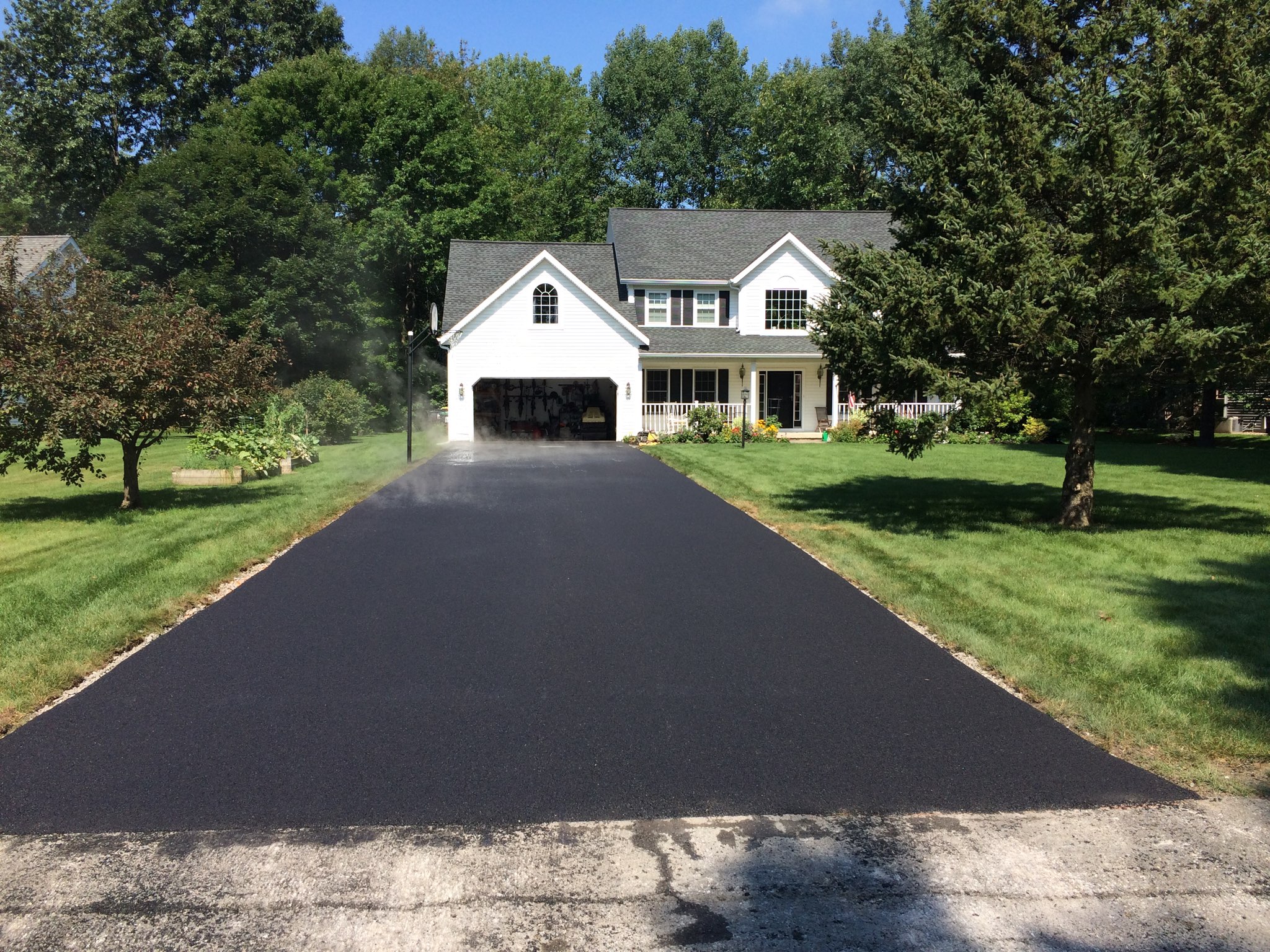 White house with a freshly-paved asphalt driveway